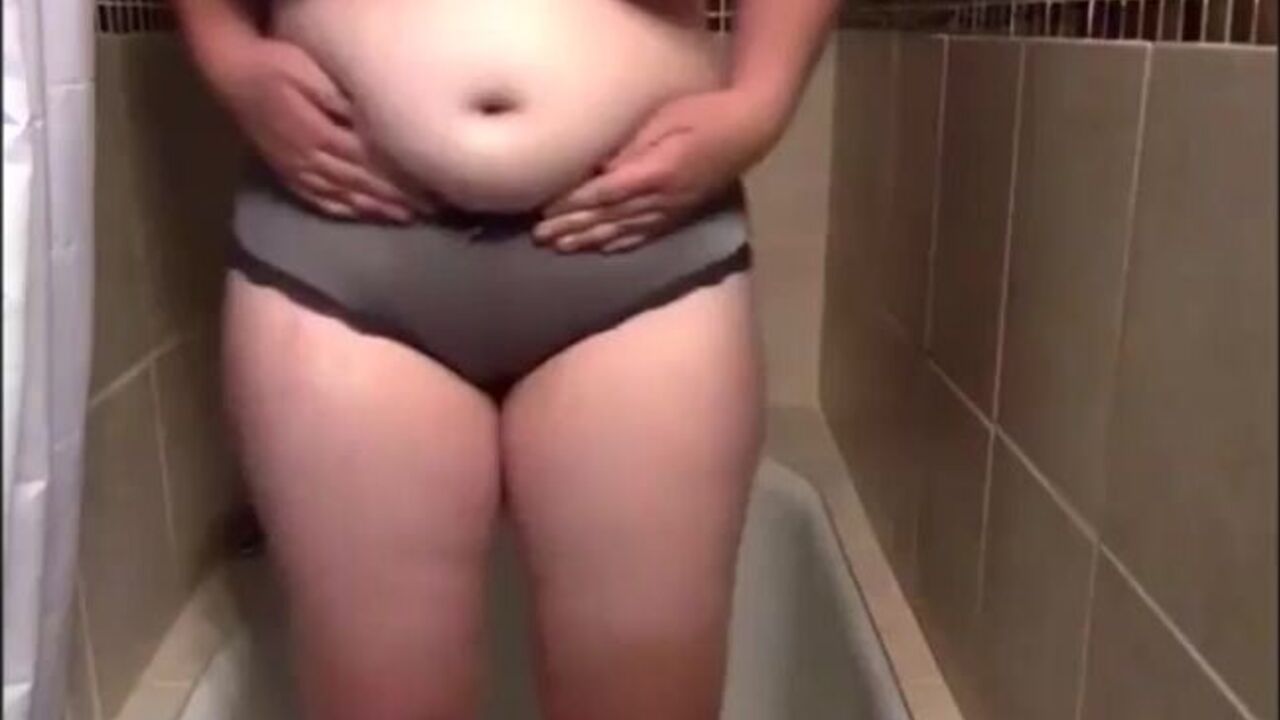 Watch this slutty babe get her big tits drenched in her own piss while standing up